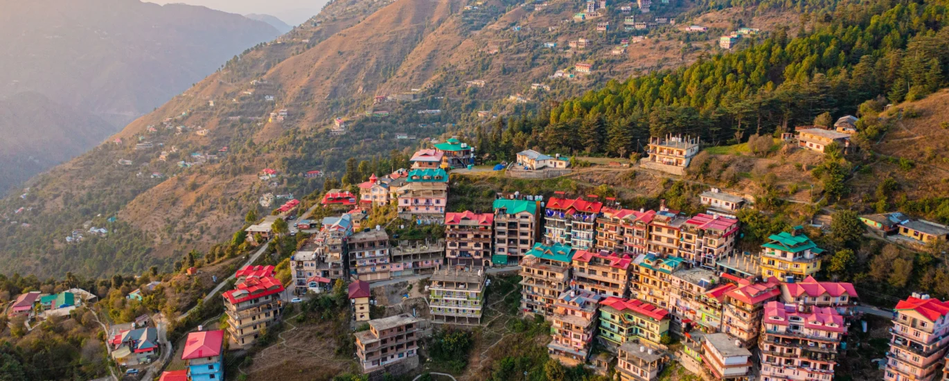 Snow-capped mountain peaks and green pine forests viewed during a Himachal tour package trip.